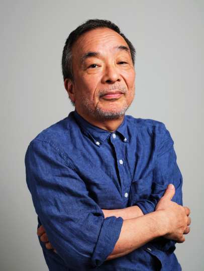 青いシャツを着て腕を組み微笑む藤幡正樹氏のポートレート写真